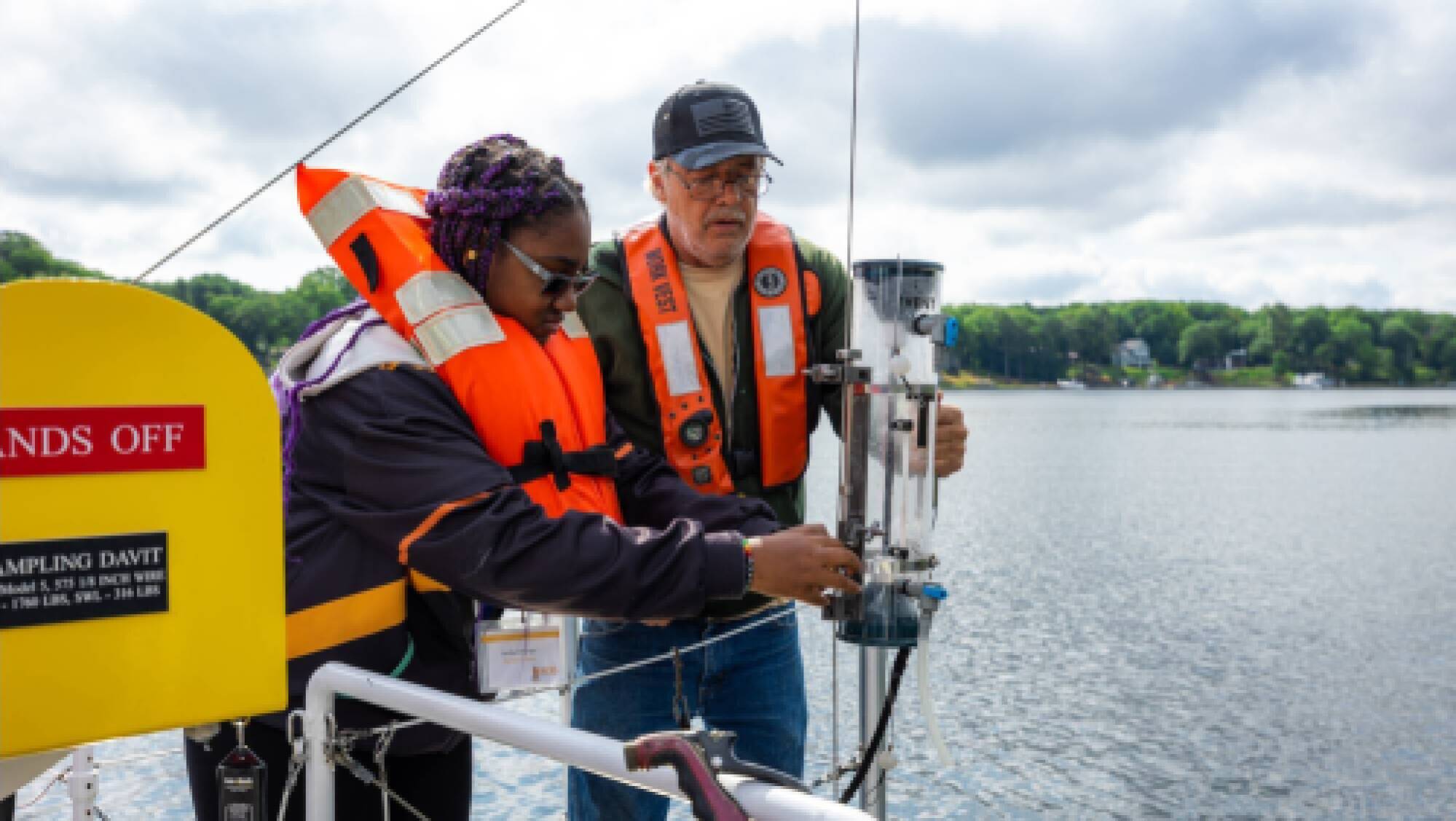 A student and deckhand collect a sample of Spring Lake water during a cruise on the D.J. Angus.